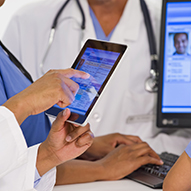 Doctors using digital tablet together in hospital.